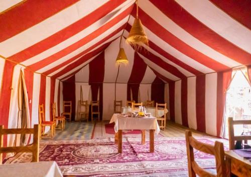 une salle à manger avec une tente rayée rouge et blanche dans l'établissement Desert Life Camp, à Merzouga