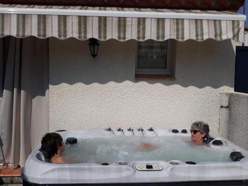 2 Personen in einer Whirlpool-Badewanne in einem Gebäude in der Unterkunft Gîte du Soleil, climatisé avec piscine chauffée d'avril à novembre, et jacuzzi in Pouzolles