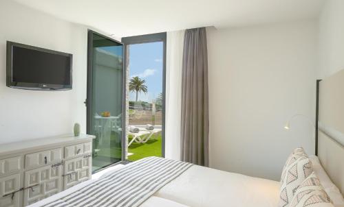 - une chambre avec un lit et une porte coulissante en verre dans l'établissement Bungalows Doña Rosa, à Playa del Ingles