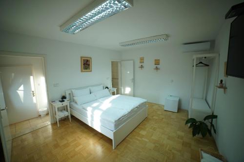a bedroom with a white bed and a wooden floor at Sobe Proštija in Ptuj