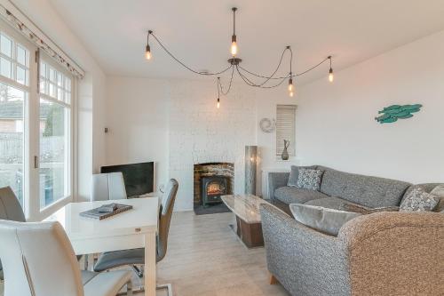 a living room with a couch and a table and a fireplace at Jurassic View Apartment in Lyme Regis