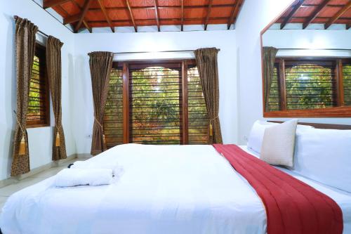 a bedroom with a large white bed with windows at SaffronStays Coorg Toddy Farms, Coorg in Madikeri