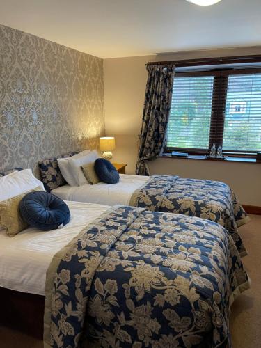 a hotel room with two beds with blue pillows at The Auld Kirk in Ballater