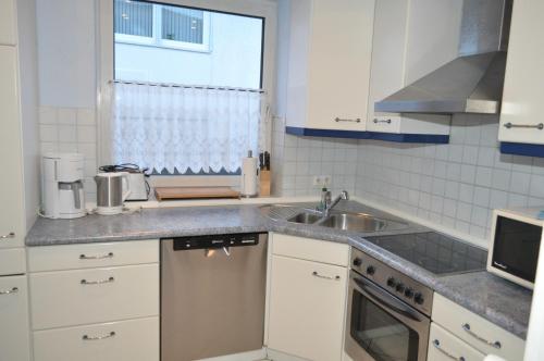uma cozinha com armários brancos, um lavatório e uma janela em Ferienwohnungen Öker - Whg 4 em Grömitz