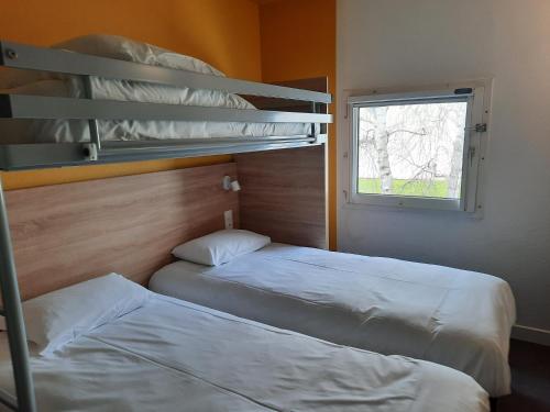 two bunk beds in a room with a window at Kyriad Direct Caen Nord Memorial in Caen