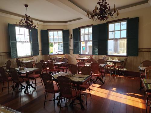 a dining room with tables and chairs and windows at Pousada do Duque in Lambari