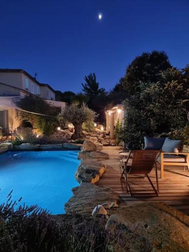 - une piscine avec une terrasse en bois et une chaise dans l'établissement Une Oasis au Pays de Cézanne, à Aix-en-Provence