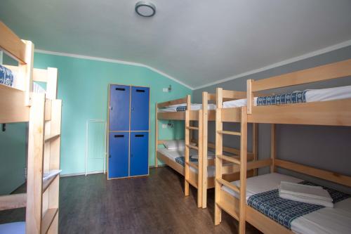 a room with several bunk beds and a blue door at Hostel Adriatic Piran in Piran