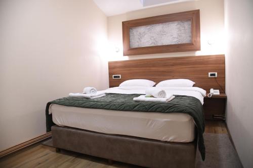 a bedroom with a large bed with a wooden headboard at Hotel Garden in Novi Sad