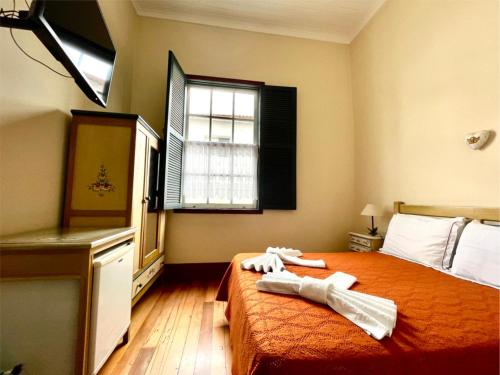 a bedroom with a bed with two towels on it at Pousada do Duque in Lambari