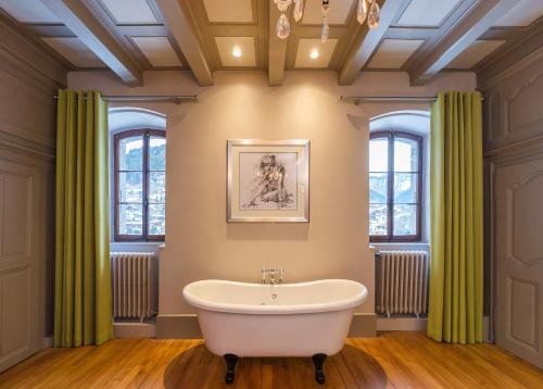 La salle de bains est pourvue d'une baignoire et de rideaux verts. dans l'établissement The Manoir, à Morzine