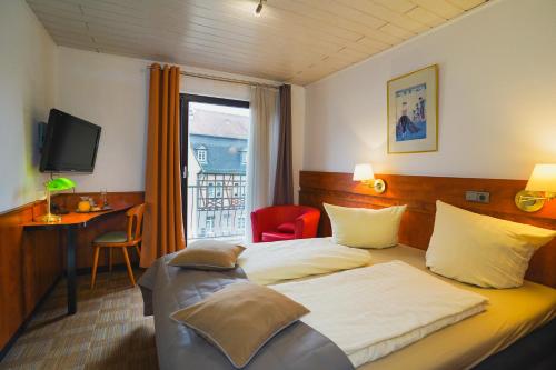 a hotel room with a bed and a desk and a window at Gästehaus Präsenzhof in Bensheim