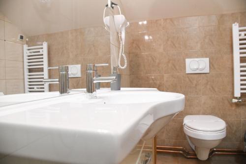 a bathroom with a white sink and a toilet at Hotel Garden in Novi Sad