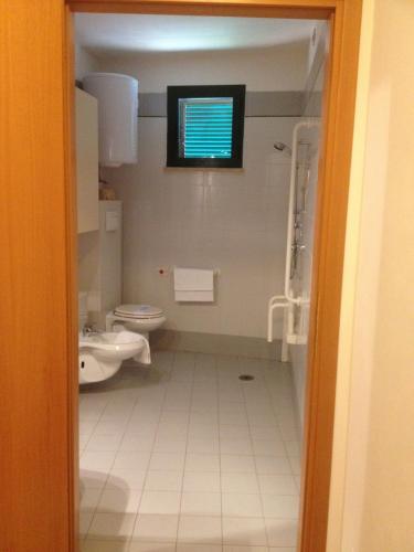 a bathroom with a toilet and a sink and a window at Villaggio Mare Si in Follonica