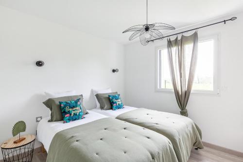 2 camas en un dormitorio con paredes blancas y ventana en La Casalina en Combrit