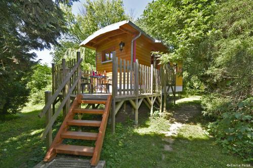 a wooden cabin with a staircase leading up to it at Roulotte La Verdine in Dury