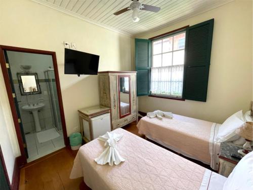 a hotel room with two beds and a sink at Pousada do Duque in Lambari