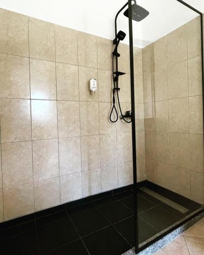 a shower with a black floor and a shower head at Hotel Ambasador Garden in Lezhë