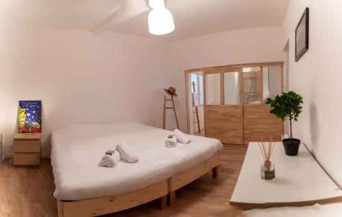 - une chambre avec un lit avec des draps blancs et une table dans l'établissement Le PETIT AVIGNONNAIS - SUAVECORAZON - INTRAMUROS - CENTER, à Avignon