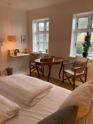 StenstrupにあるFeriehus i skøn naturのベッドルーム1室(ベッド1台、テーブル、椅子付)