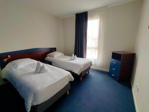 a hotel room with two beds and a window at Comfort Aparthotel Carcassonne in Carcassonne