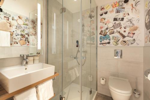 a bathroom with a shower and a sink and a toilet at Holiday Inn - the niu, Mill Cologne Mülheim by IHG in Cologne