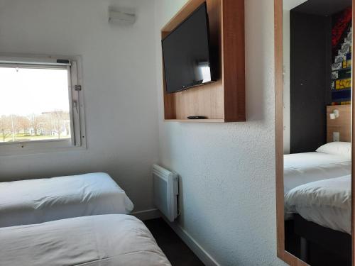 a small room with two beds and a tv at Kyriad Direct Caen Nord Memorial in Caen