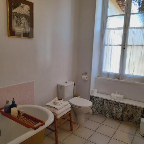 une salle de bain avec toilettes, baignoire et lavabo dans l'établissement L'Impasse du Temple, à Léran