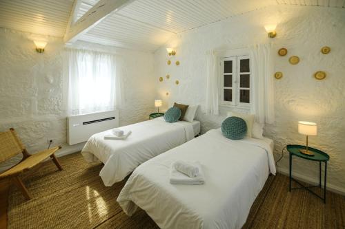 two beds in a white room with two chairs and a window at Majestic Villa in Amarante with Private Pool in Amarante