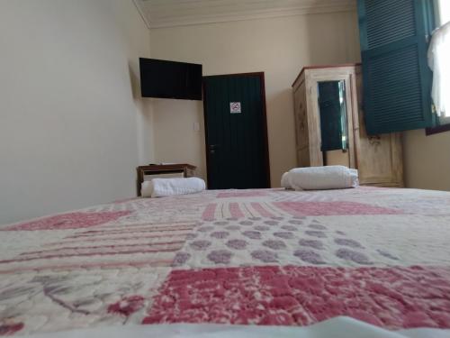 a bedroom with a large bed with a red and gray blanket at Pousada do Duque in Lambari