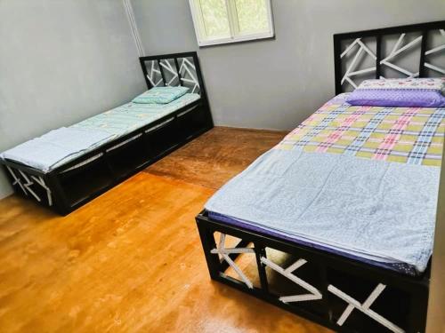 two twin beds in a room with wooden floors at OYO Home 90491 Flinstone Lodge in Kota Kinabalu
