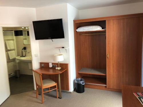 a hotel room with a desk and a tv and a bedroom at Hotel Garni Rabennest in Braubach