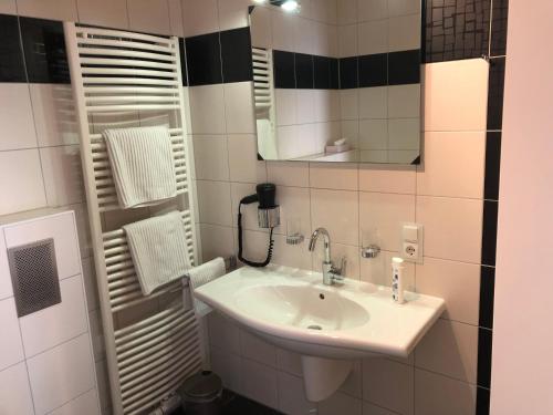 La salle de bains est pourvue d'un lavabo et d'un miroir. dans l'établissement Hotel Garni Rabennest, à Braubach