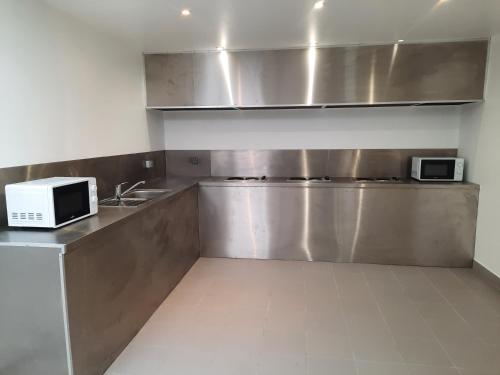 a kitchen with a sink and a microwave on a counter at Kyriad Direct Caen Nord Memorial in Caen