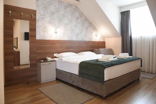 a bedroom with a large bed and a mirror at Hotel Garden in Novi Sad