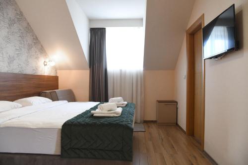 a hotel room with a bed and a flat screen tv at Hotel Garden in Novi Sad