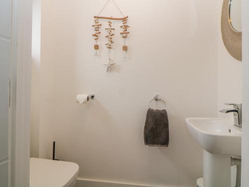 a white bathroom with a toilet and a sink at Driftwood in Torquay