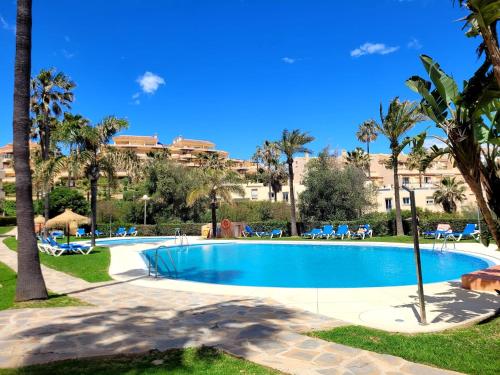una piscina con palmeras y un edificio de fondo en Casa Sierra Marina, en Mijas Costa