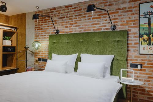 een slaapkamer met een wit bed en een bakstenen muur bij ONE66 Hotel in Ljubljana