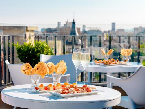 two tables with food and glasses of champagne on a balcony at H10 Universitat in Barcelona