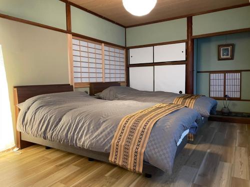 a bedroom with a bed with blue walls and windows at えん吉野絶景広がる隠れ家1棟貸切ペットokサウナ室完備 in Yoshino