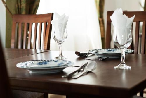 a wooden table with two plates and glasses on it at Hotel Cristian in Afumaţi
