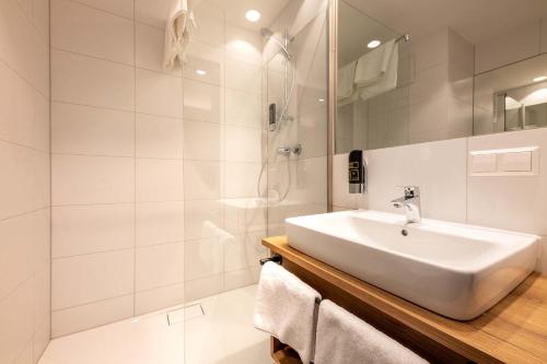 a white bathroom with a sink and a shower at Sleep in Premium Hotel Eggenburg in Eggenburg