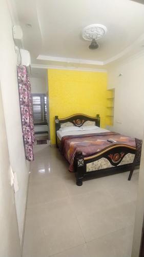 a bedroom with a bed and a yellow wall at Kushi HomeStay Guest House in Visakhapatnam