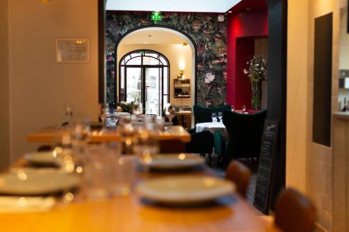 uma mesa longa num restaurante com mesas e cadeiras em Grand Place Hôtel "Boutique et Appart'hôtel" em Arras