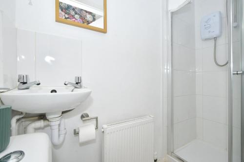 a white bathroom with a sink and a shower at London House by YourStays - 5 Bedroom House in Newcastle-under-Lyme in Stoke on Trent
