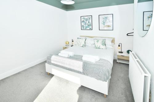 a white bedroom with a white bed with pillows at London House by YourStays - 5 Bedroom House in Newcastle-under-Lyme in Stoke on Trent