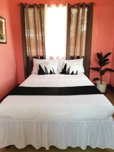1 dormitorio con 1 cama blanca grande y ventana en Agimats Crib Palawan, en Puerto Princesa City