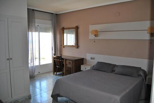 ein Schlafzimmer mit Bett, Schreibtisch und Fenster in der Unterkunft Hotel Hoya in Noja