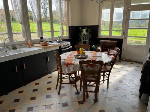 una cucina con tavolo, sedie e finestre di chambres d'hôtes et Gîte Le Moulin Sainte Marie a Estrée-Wamin